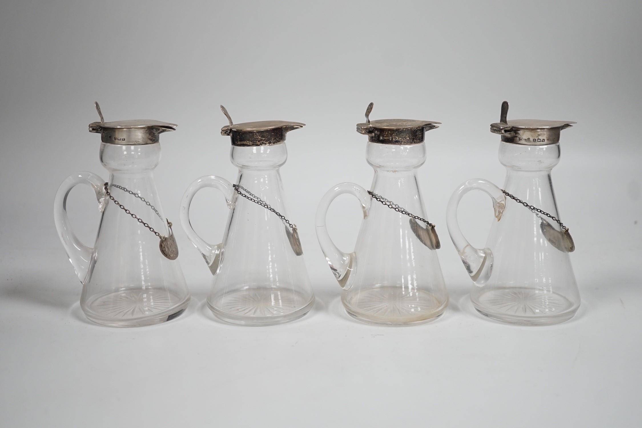 A set of four Edwardian silver mounted glass whisky noggins, H.B. Johnson & Co, Birmingham, 1909, height 12cm, together with a set of four silver whisky labels, same maker, London, 1910.